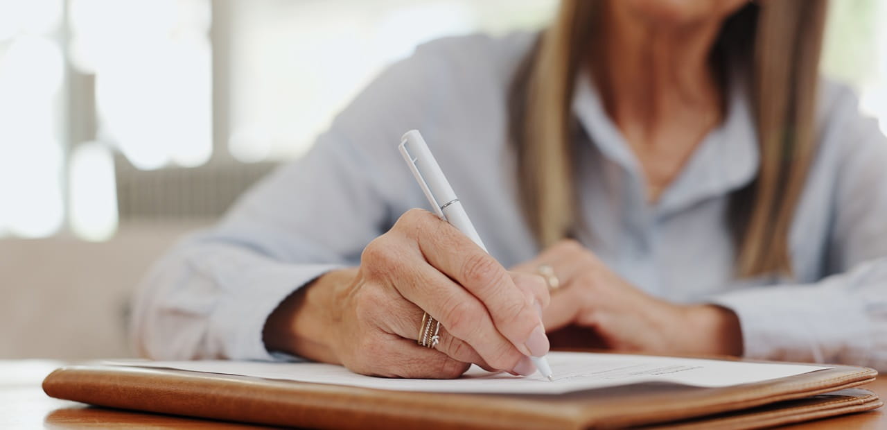 Close-up view of woman writing on a document.