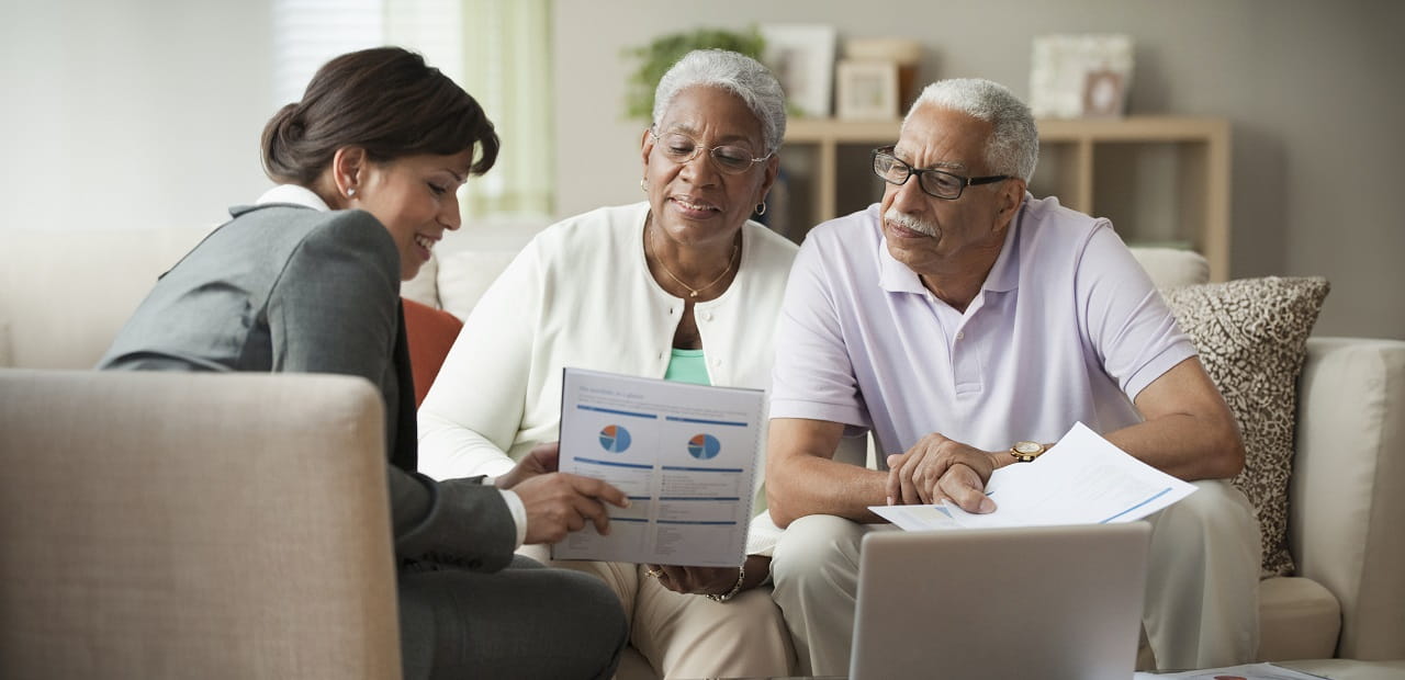 Senior couple reviewing financial documents with a professional. 